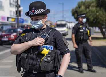 A police officer wearing a face mask talks into their radio whilst on patrol on Southend seafront.